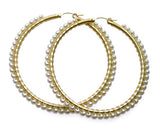 A pair of large gold hoop earrings decorated with rows of small white pearls, displayed on a clean white background.
