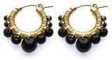 Pair of hoop earrings with gold wire and black beads on a white background