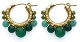 Gold hoop earrings with green beads on a white background